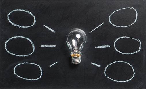A light bulb surrounded by empty chalk-drawn circles on a black chalkboard.