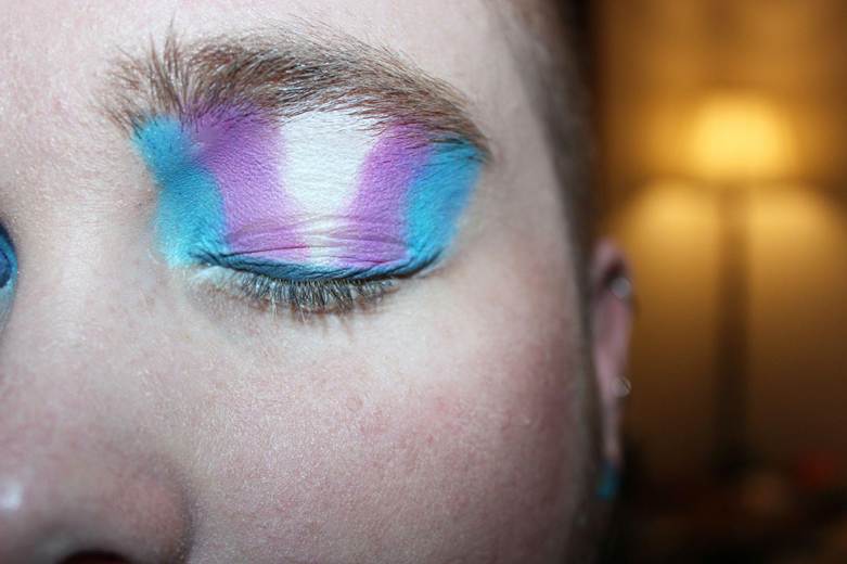 Close-up of an eye with colorful makeup featuring shades of blue, purple, and white.