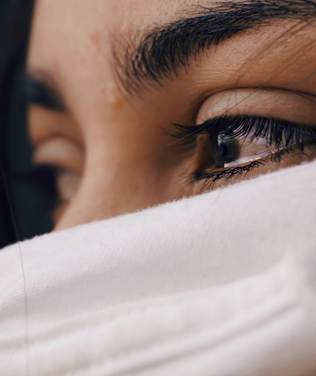 Close-up of a person's eye partially obscured by a white cloth, conveying a sense of introspection.